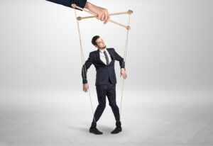 Puppet businessman controlled by giant hand.