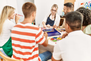 Employees finger painting during corporate art therapy session to relieve workplace burnout.