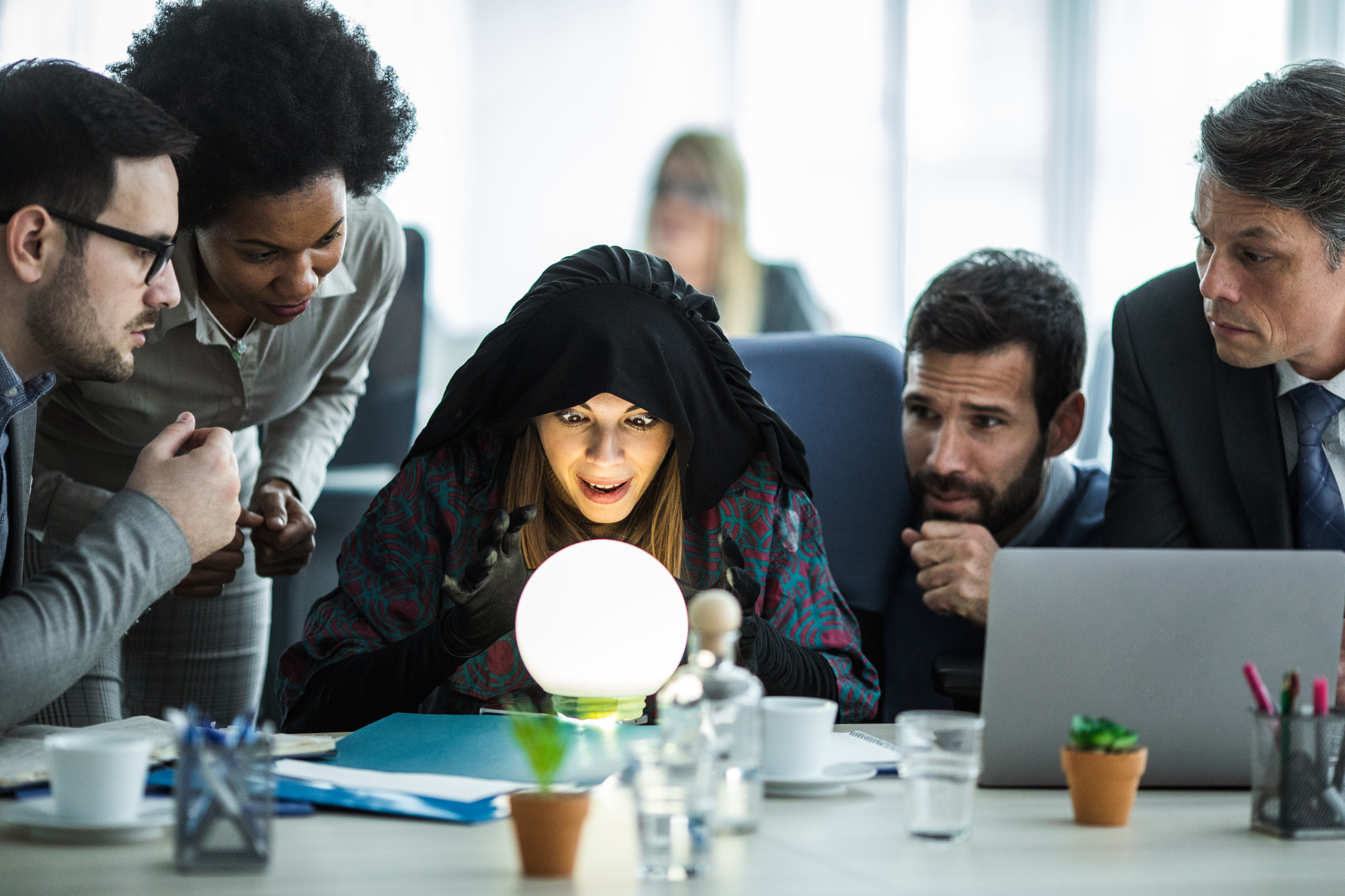 A fortune teller with a glowing crystal ball surrounded by anxious office workers.