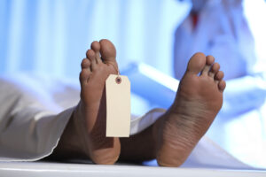 Satirical image of a body with a toe tag, representing new sick-day death certificate policy.