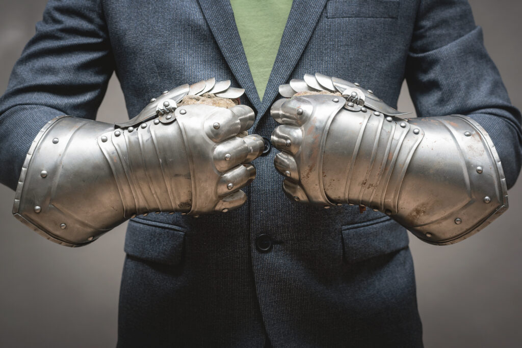 Corporate warrior in a business suit and medieval gauntlet gloves preparing for battle.