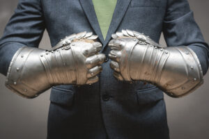 Corporate warrior in a business suit and medieval gauntlet gloves preparing for battle.