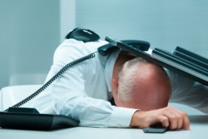 Exhausted office worker collapsed on their desk, symbolizing corporate burnout and extreme overwork.