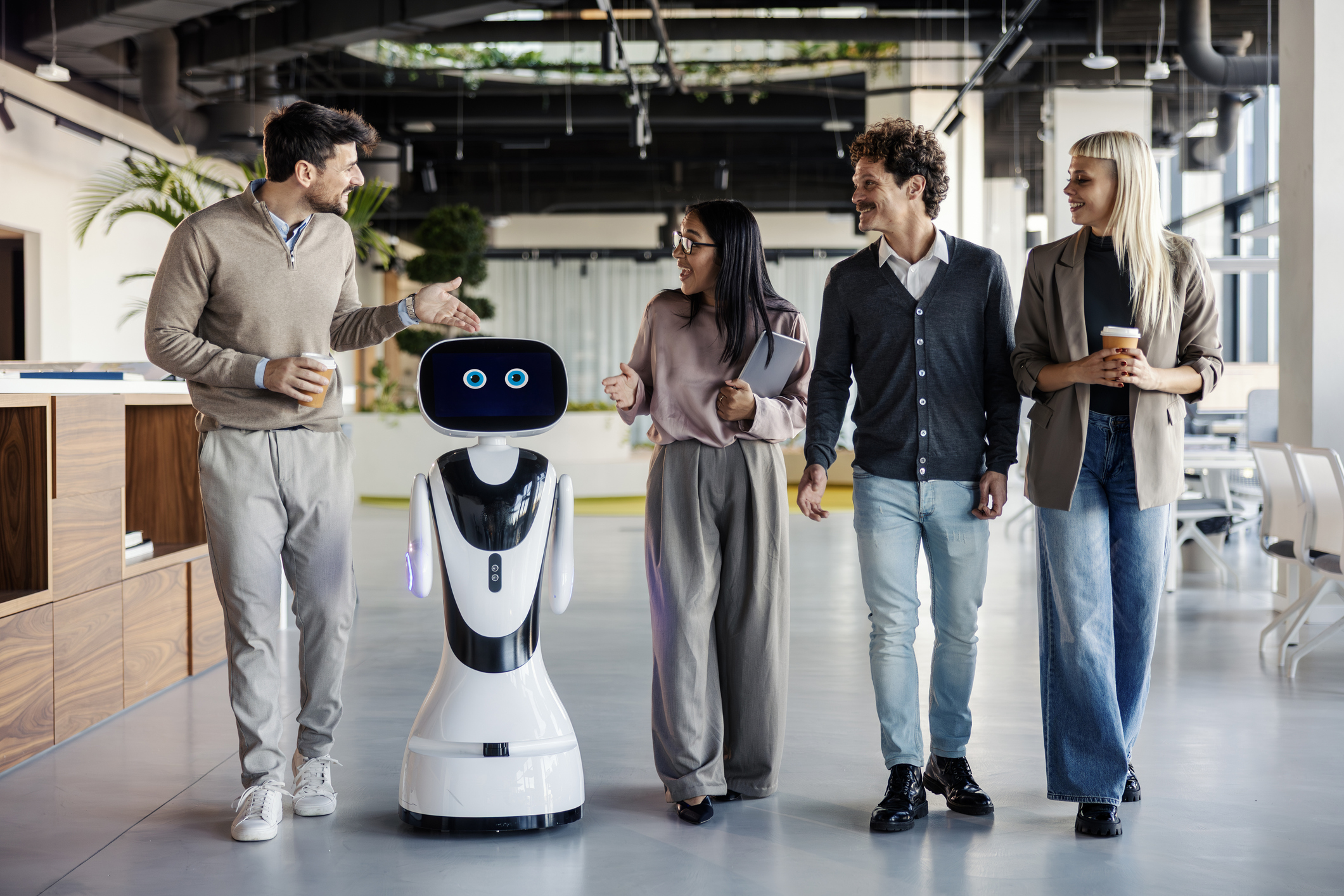 Office staff excitedly chatting with a smiley robot assistant, each person subtly hoping the bot doesn’t steal their job before lunch.